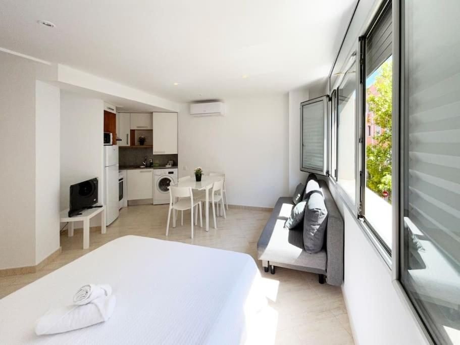 Piso M2: cama, sofá junto a la ventana y cocina al fondo